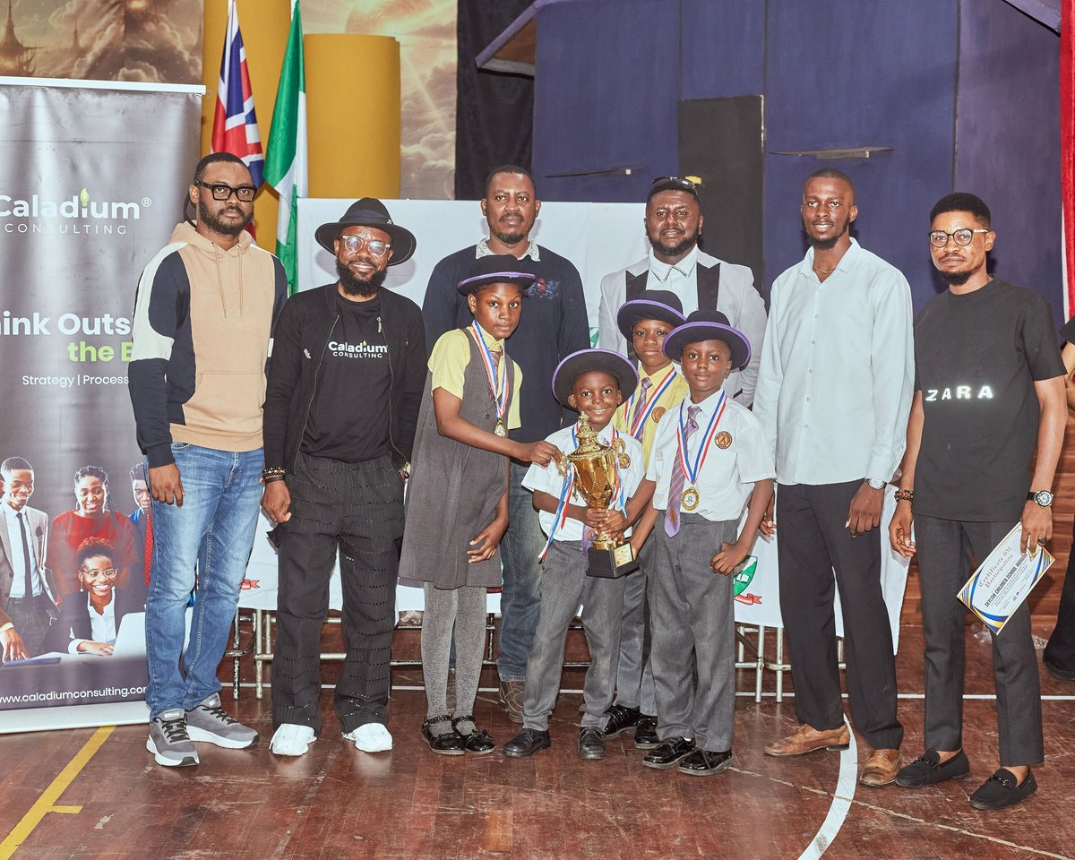 Group of men posing together at an indoor event with flags and branding visible in background